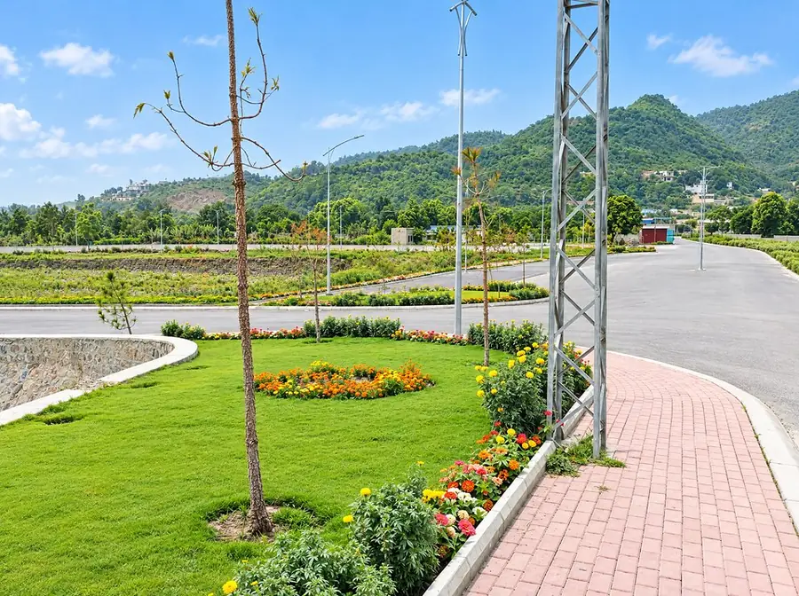 Lawn and flower bed beside a footpath, with the hills behind
